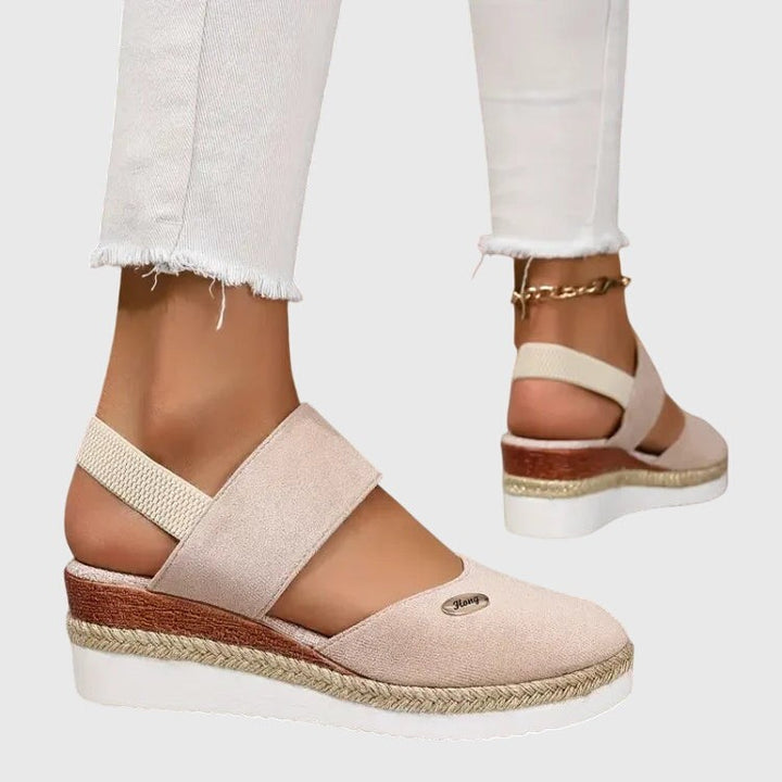 Cream suede platform sandal featuring crisscross elastic straps and jute sole