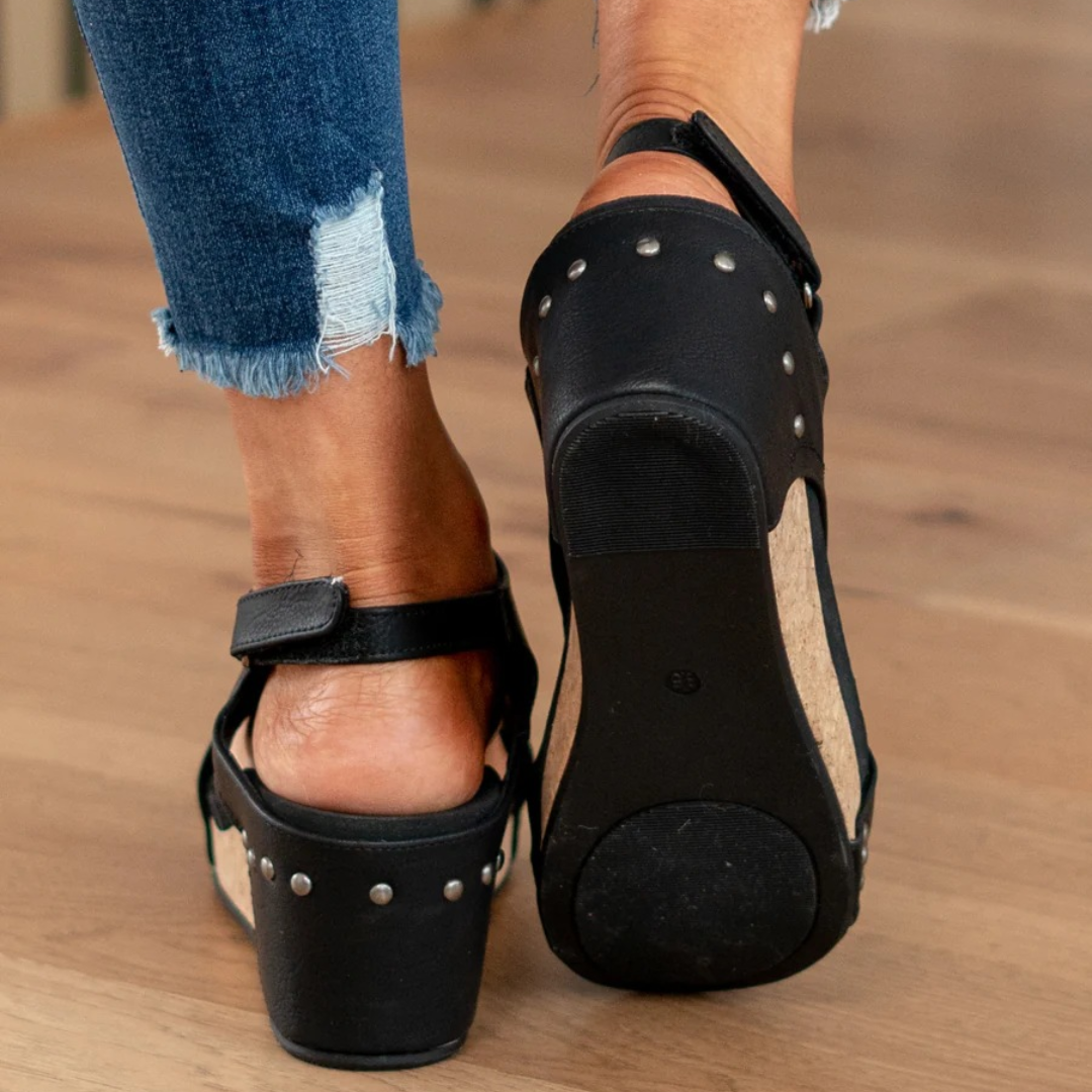 Close-up of black studded wedge sandals showing textured sole