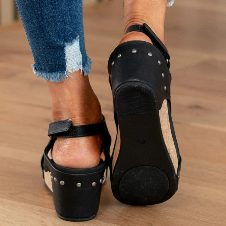 Close-up of black studded wedge sandals showing textured sole