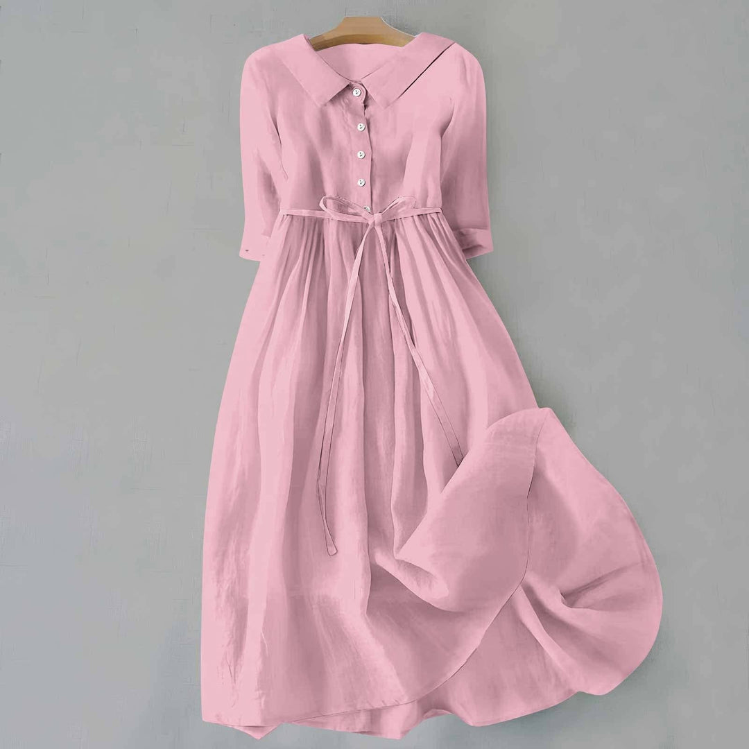 Pink linen shirt dress with collared neck, buttons, and flowing skirt