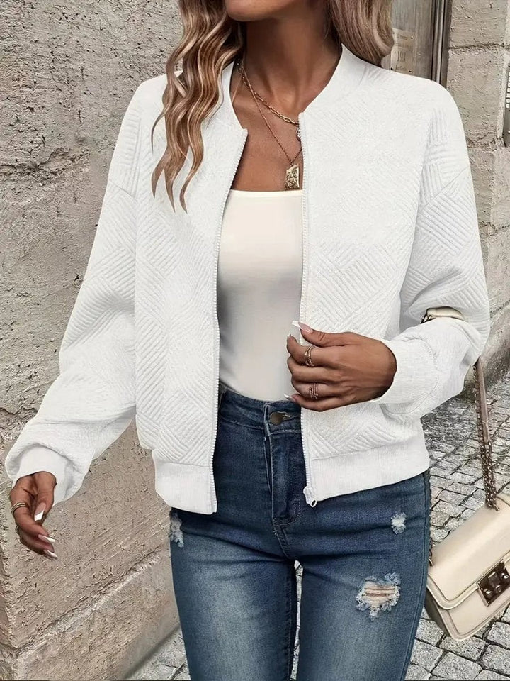 White textured bomber jacket with zip-up front, worn over a cream vest top