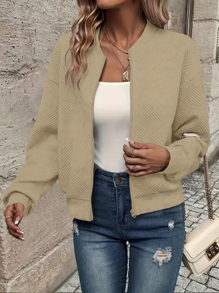 Beige textured zip-up bomber jacket paired with a white cami top