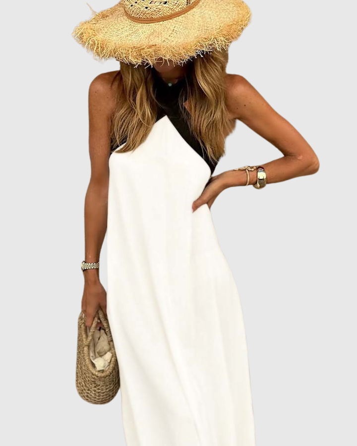 Flowy white halter maxi dress paired with woven straw handbag