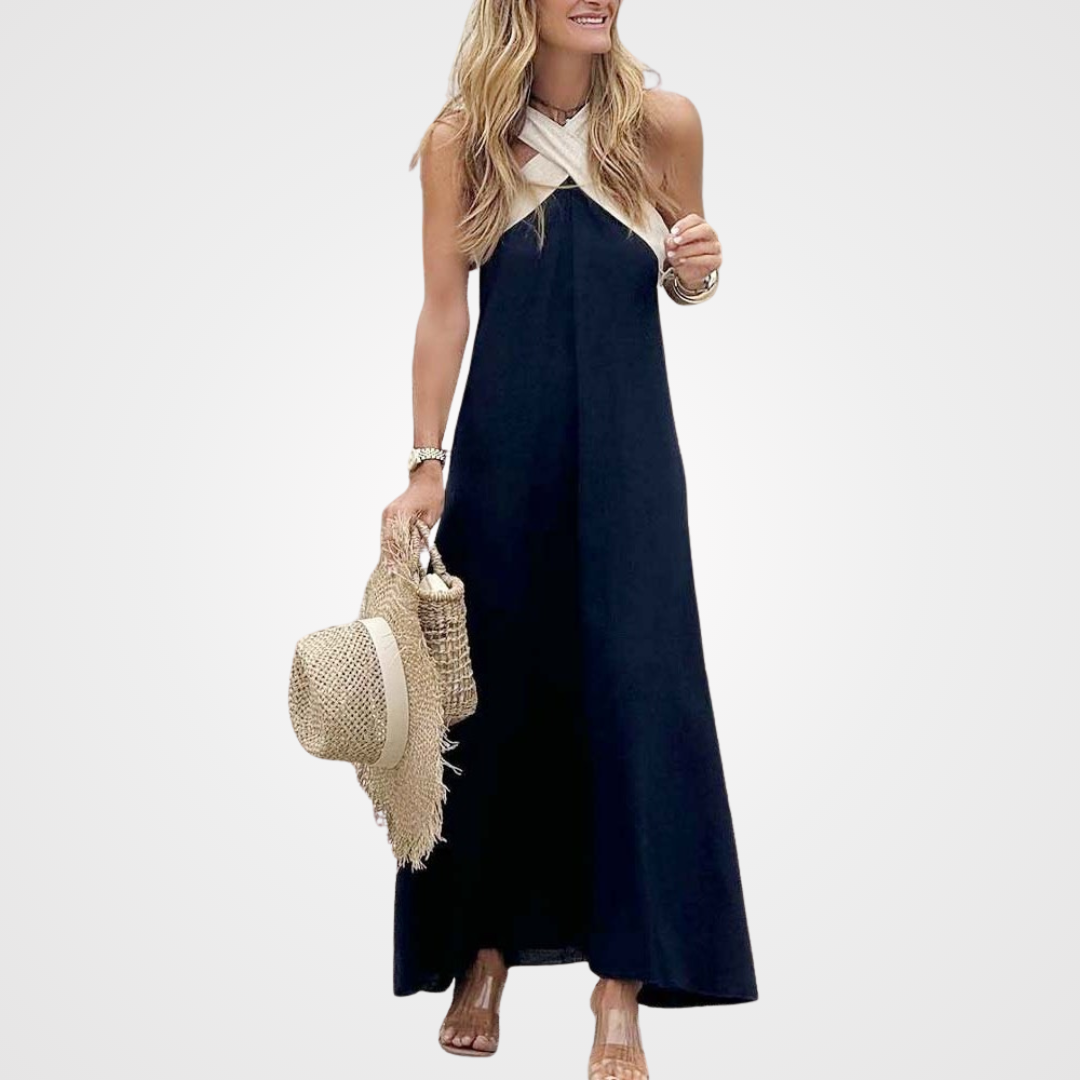 Navy maxi dress with beige crisscross halter neckline and straw bag