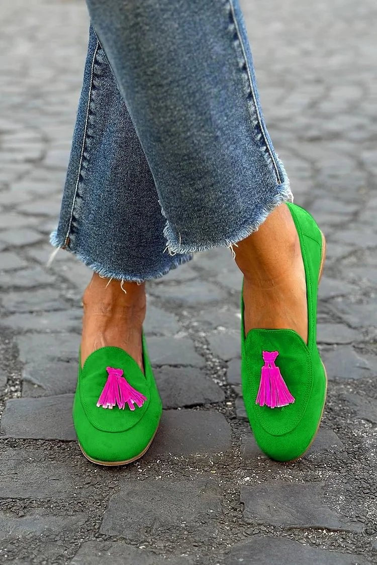 Green suede slip-on loafers with pink tassel detail, worn with cropped jeans