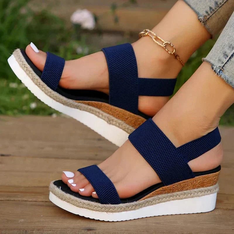 Navy blue open-toe wedge sandal with elastic straps and cork-look platform