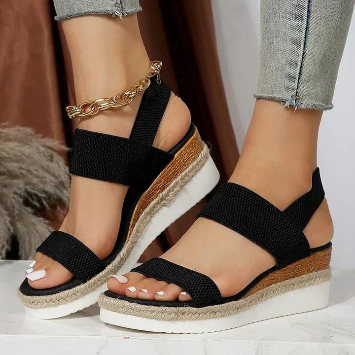Black espadrille wedge sandal showing crisscross straps and open toe design