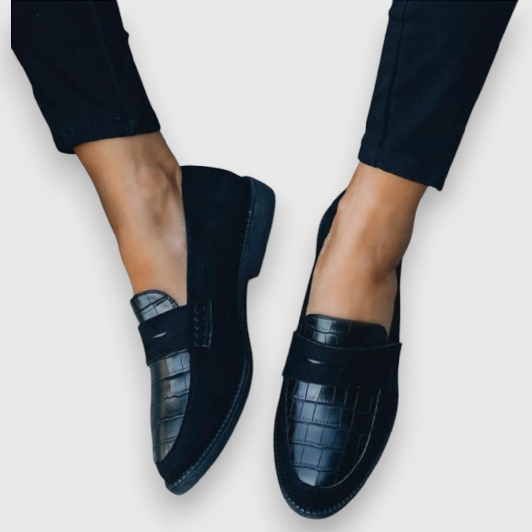 Black penny loafers with croc-embossed toe worn with cropped black pants