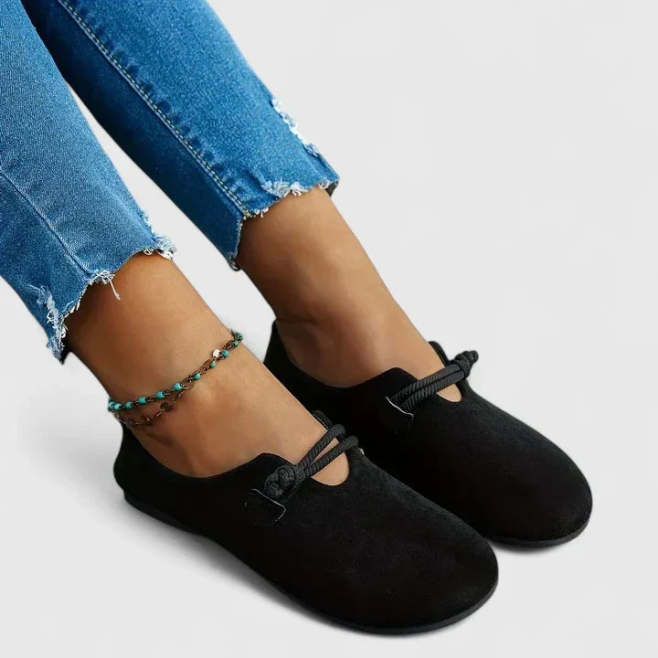 Black suede loafers styled on feet with ripped denim jeans