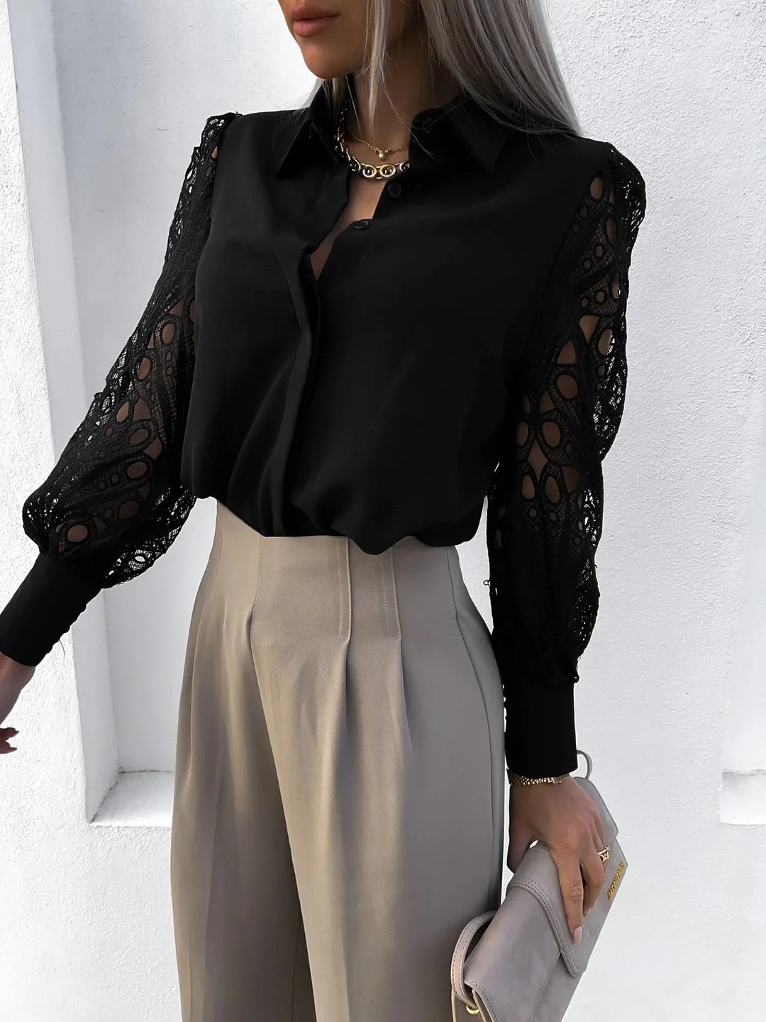Black button-down blouse showing intricate cutout lace long sleeves close-up
