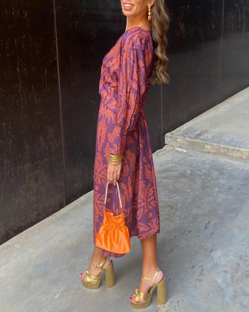 Purple paisley maxi dress styled with gold platform sandals and orange clutch