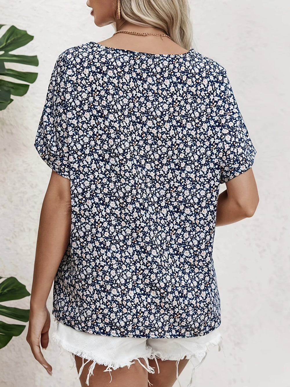 Back view of navy ditsy floral blouse showing round neckline and relaxed short sleeves
