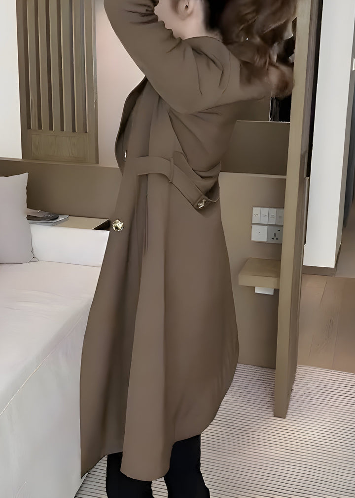 Model adjusting sleeve of taupe wool trench coat with wide collar
