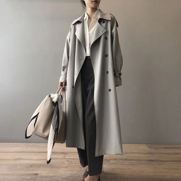 Grey double-breasted trench coat worn with tailored black trousers and tote bag