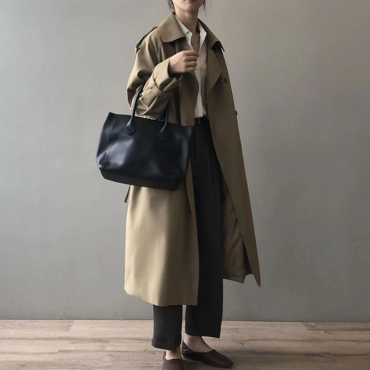 Khaki double-breasted trench coat styled with black leather tote and cropped trousers