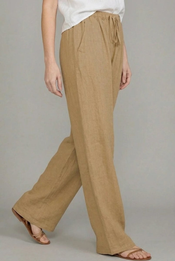 Side view of tan linen wide leg pants with drawstring waist, worn with sandals