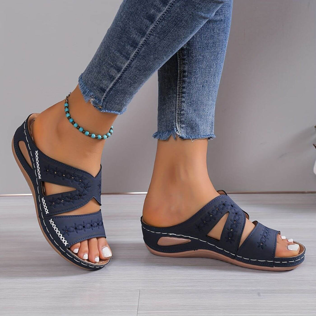 Navy blue wedge sandals with cutout straps and stitched floral embroidery detail