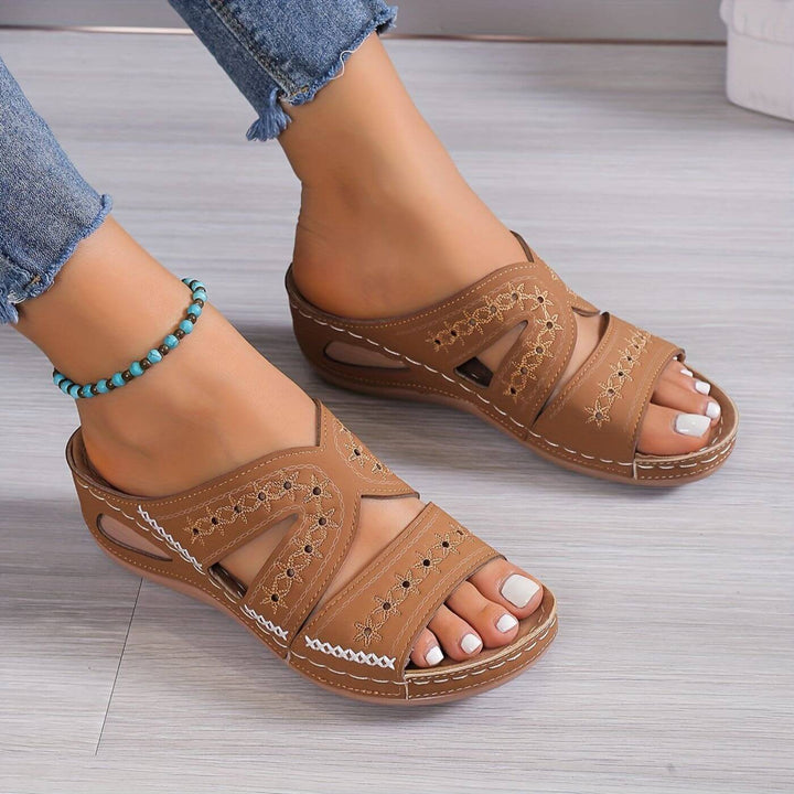 Tan wedge sandals with floral stitching and crisscross cutout straps