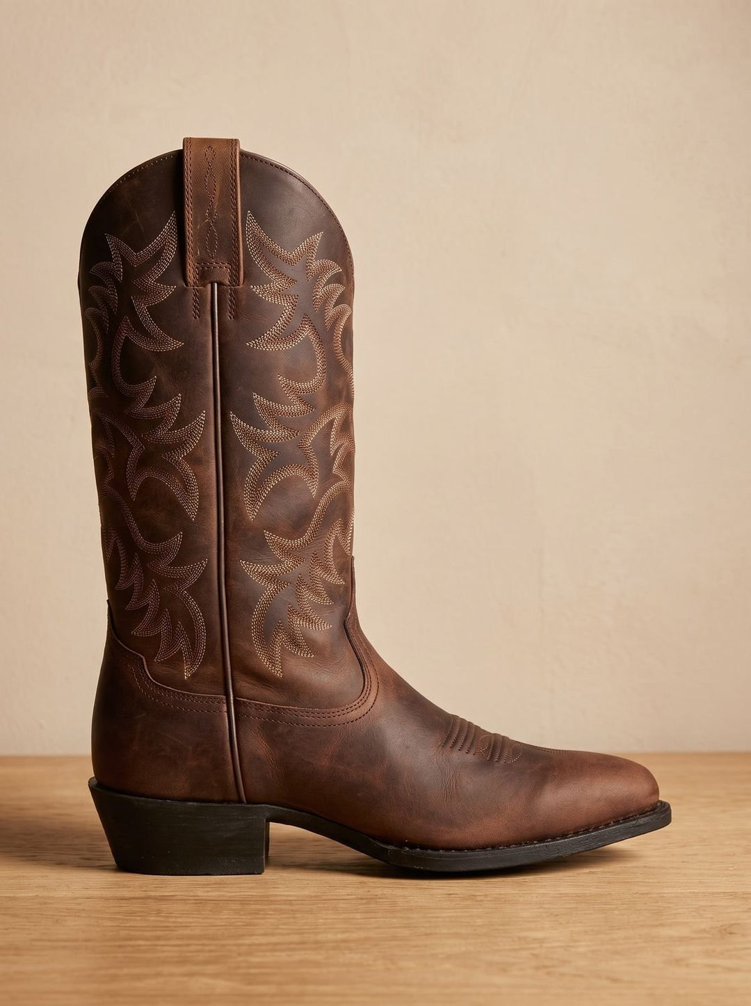 Side view of brown leather cowboy boot with intricate embroidered stitching on shaft