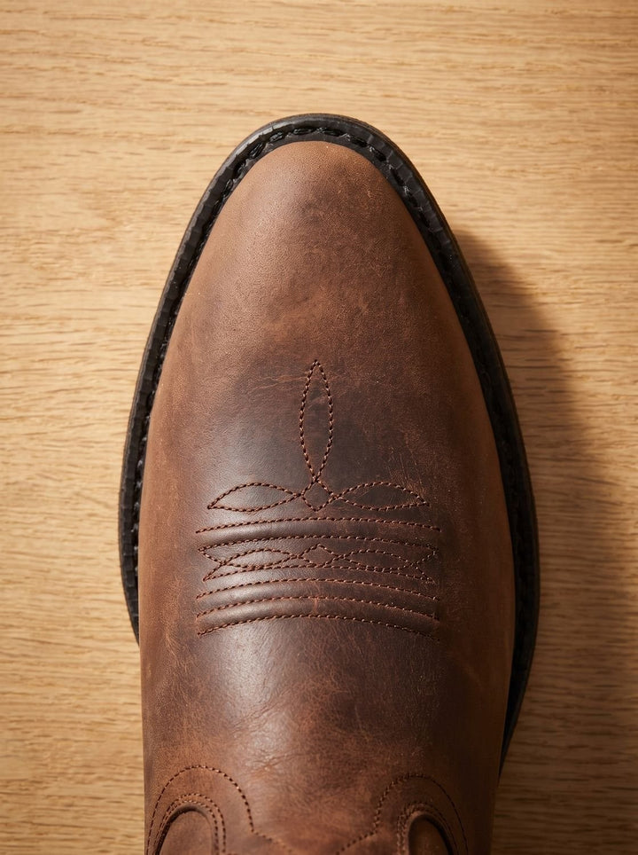 Close-up of brown leather cowboy boot toe with decorative topstitching