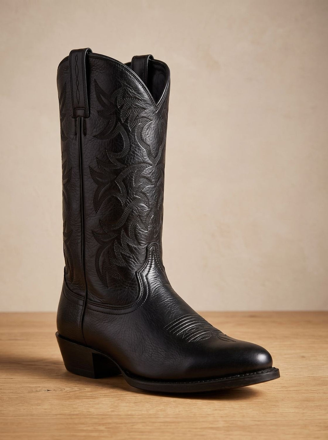 Black leather cowboy boot with embroidered shaft standing at a slight front angle