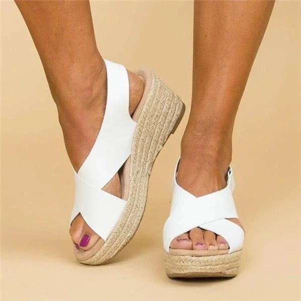 White espadrille wedge sandals featuring crossover straps and woven jute platform