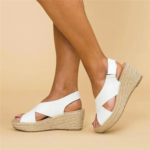 White espadrille sandals showing crossover straps and ankle buckle closure