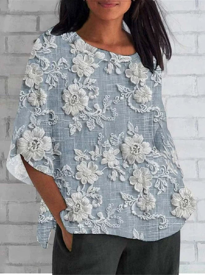Light blue floral embroidered blouse with three-quarter sleeves and round neckline