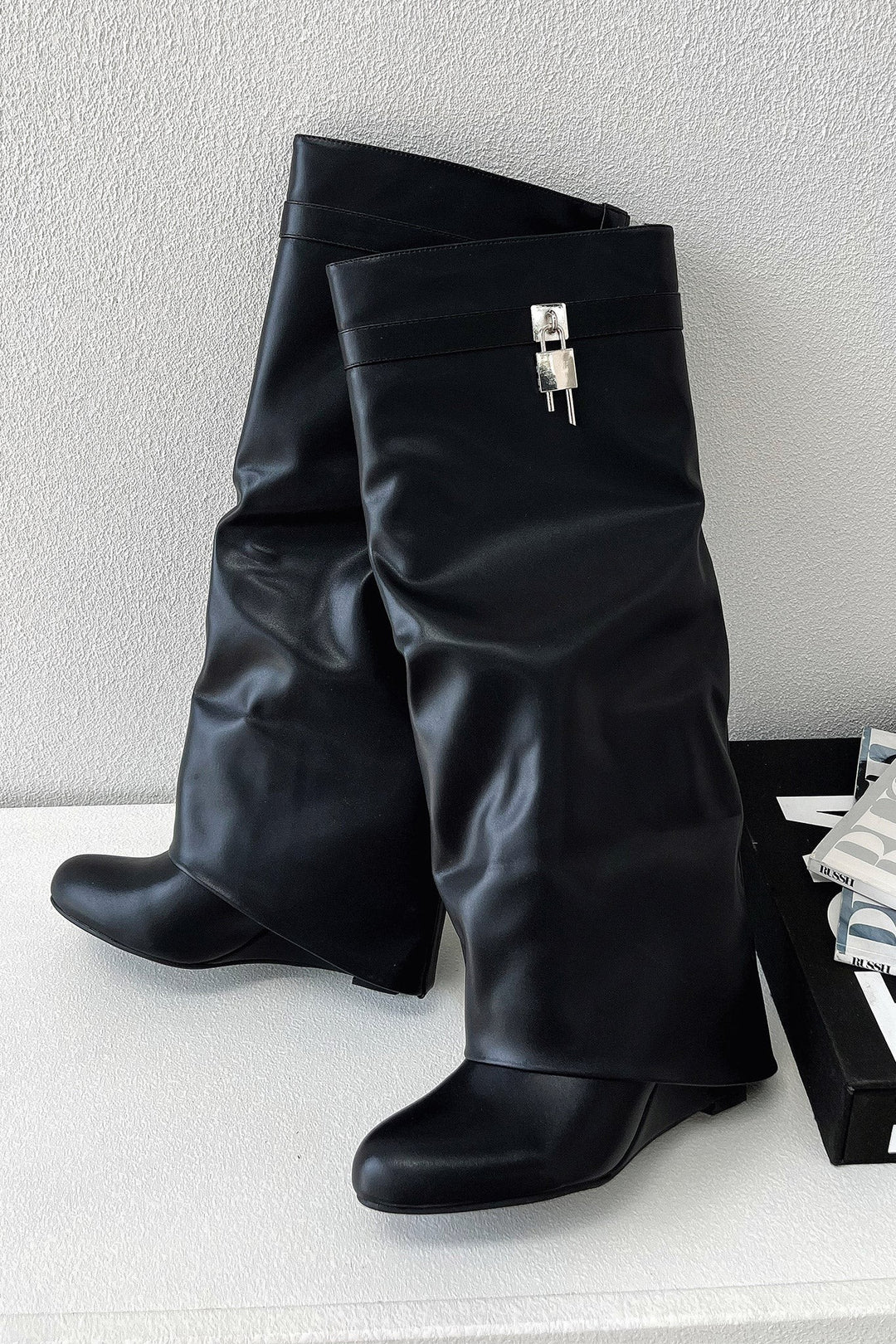black knee-high foldover boots with silver lock charm, displayed against white backdrop