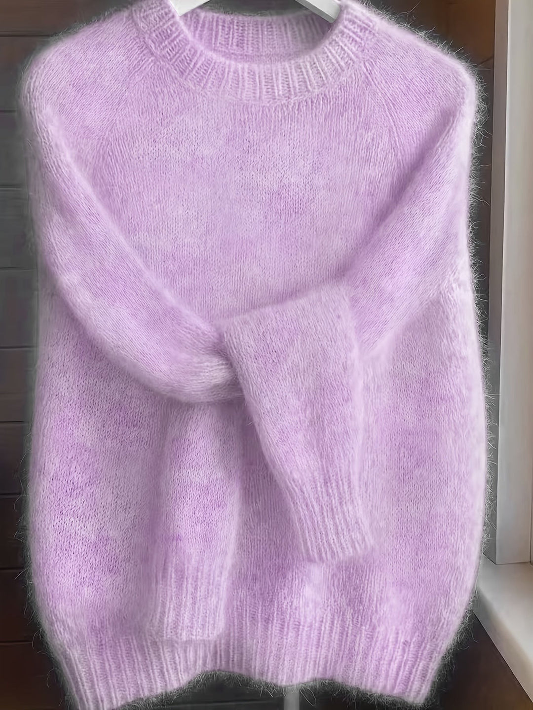 Lilac fuzzy knit jumper with ribbed hem draped on a hanger