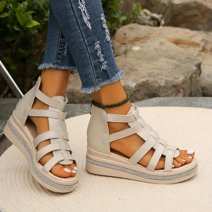beige open-toe wedge sandals with caged ankle strap and rhinestone edge