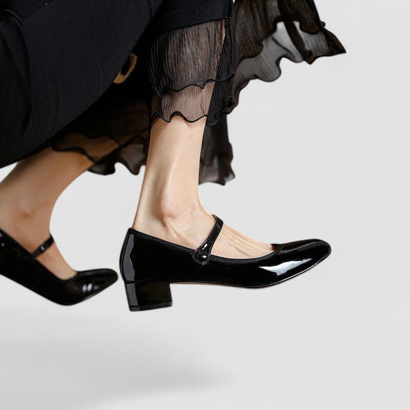 Black patent Mary Jane heels shown mid-step with sheer ruffled hem
