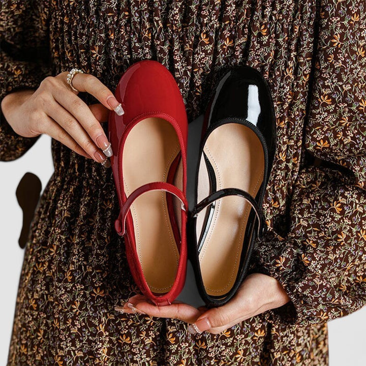 Red and black patent leather Mary Jane shoes held side by side