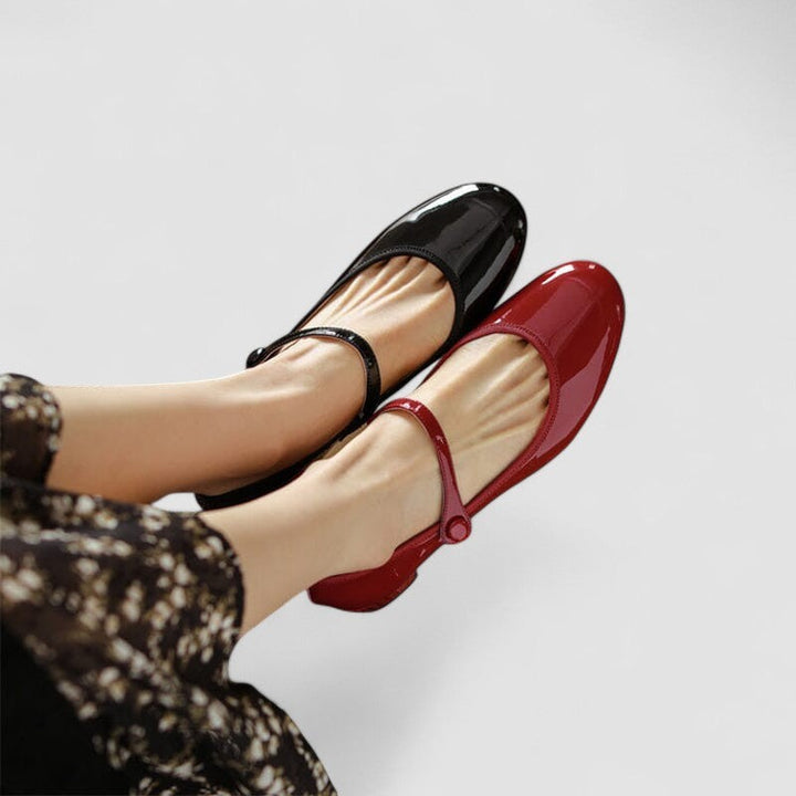 Black and red patent Mary Jane flats crossed at the ankle