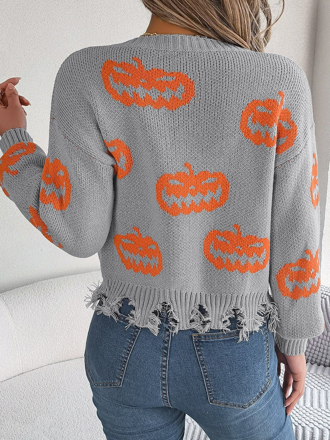 Woman modeling black Halloween sweater with orange pumpkin faces