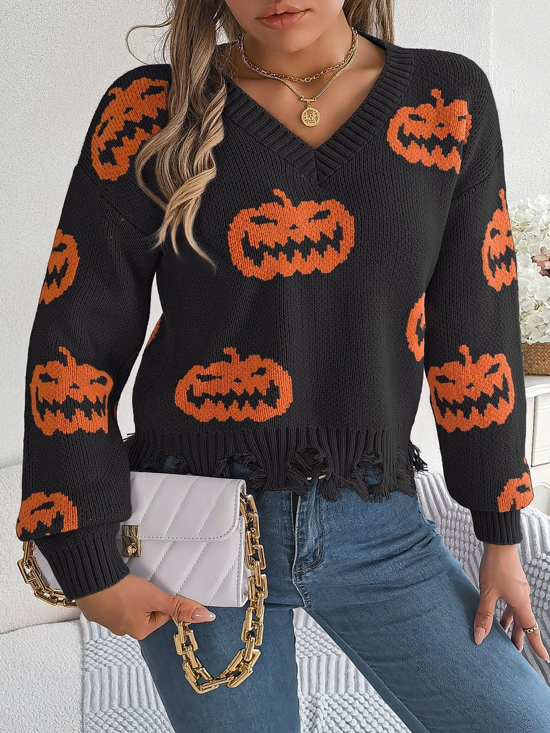 Close-up of black pumpkin print sweater with tattered knit hemline