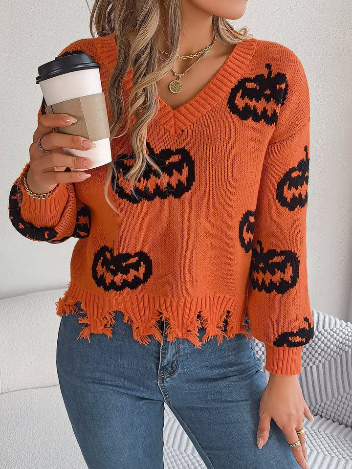 Woman holding coffee cup in orange pumpkin print sweater with raw hem