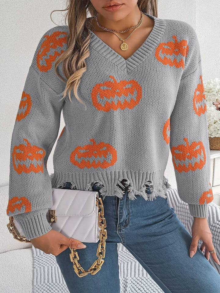 Close-up of gray knit sweater with orange pumpkin print and frayed hem
