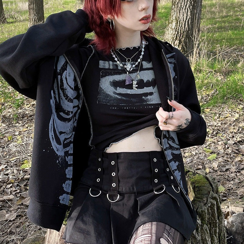 Skeleton print zip-up hoodie worn open over a graphic crop top outdoors