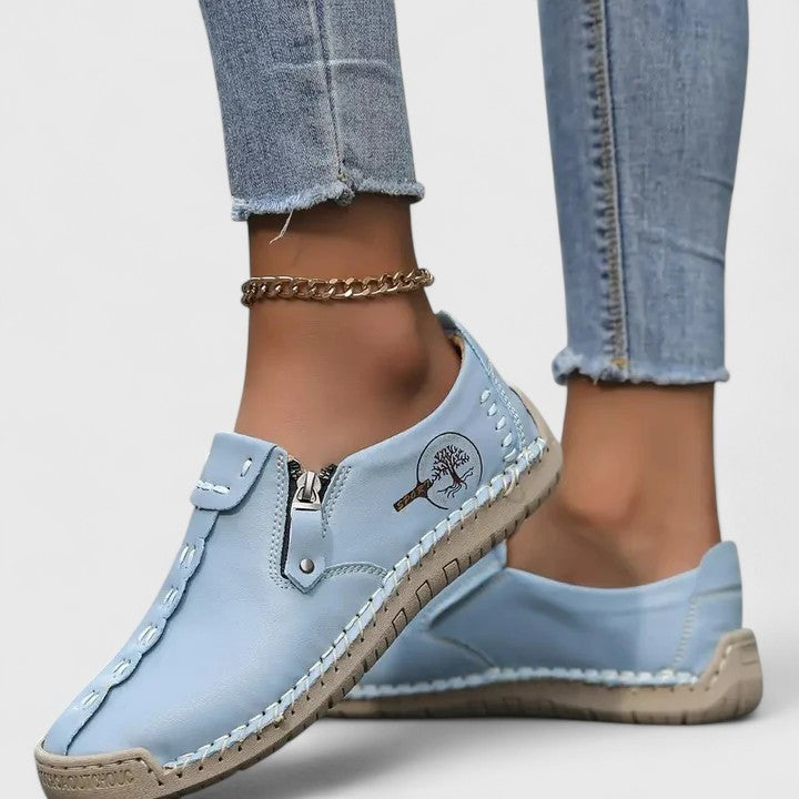 Light blue leather slip-on sneakers with side zipper and tree logo accent