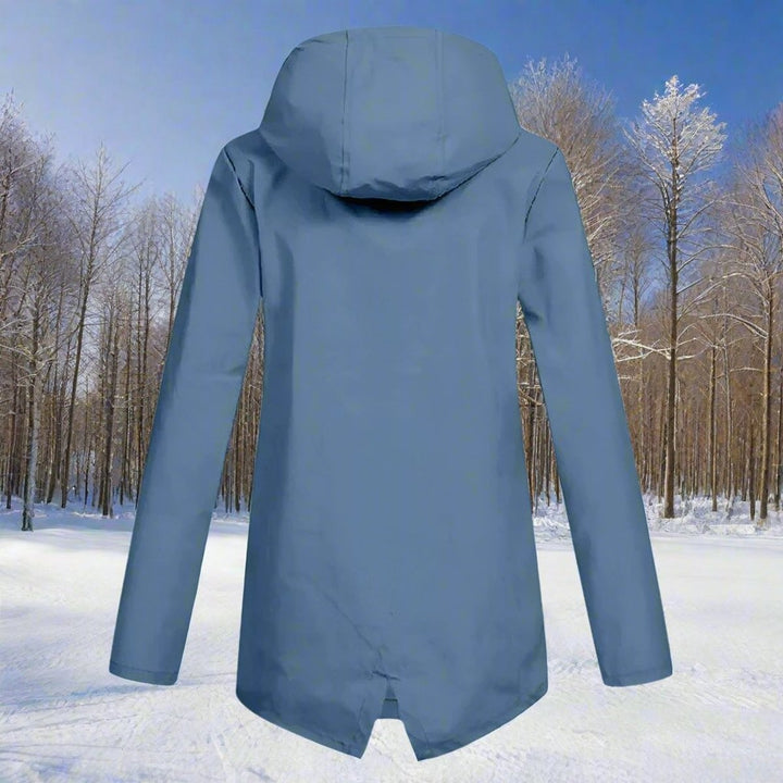 Slate blue longline rain jacket back view with hood in snowy forest setting