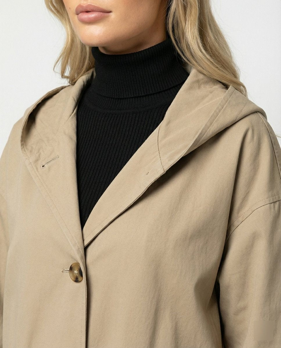 Close-up of beige trench coat hood, lapel and horn-style button detail