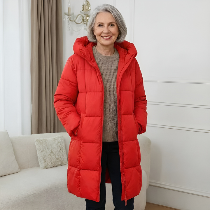 Red longline hooded puffer coat worn with a knit sweater and jeans
