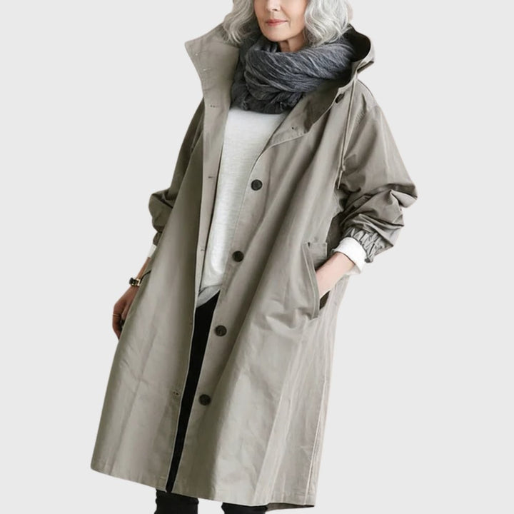 Taupe hooded trench coat with button front worn over a scarf and sweater