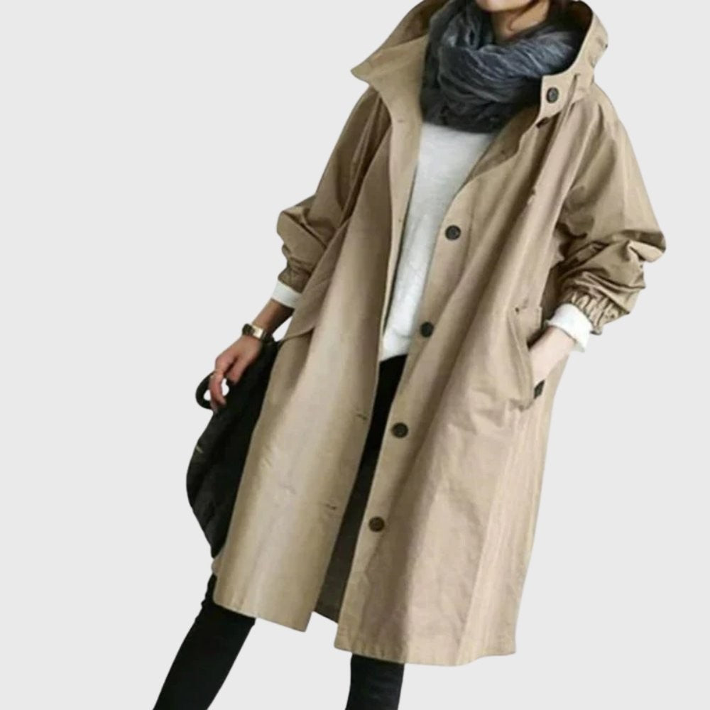 Khaki hooded trench coat layered over a white sweater and black pants