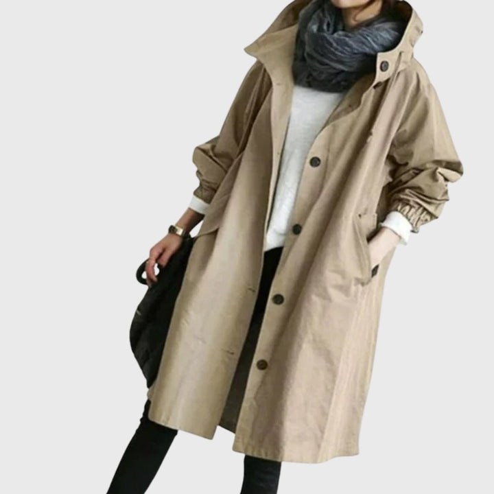 Khaki hooded trench coat layered over a white sweater and black pants