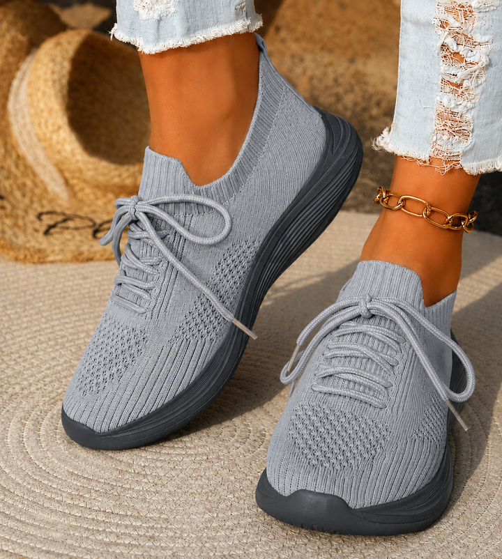 Gray knit lace-up sneakers with contrast sole worn with ripped jeans