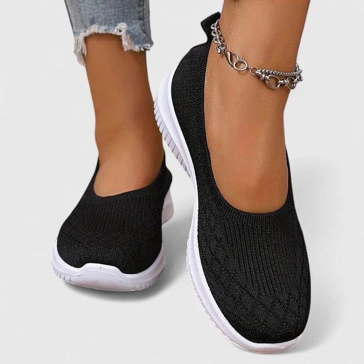 Black knit slip-on sneakers featuring breathable mesh and cushioned white sole