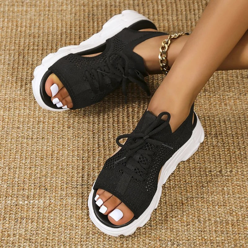 Black knit sandals with side cutouts paired with a chunky white outsole