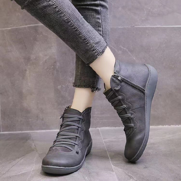 Woman wearing gray leather ankle boots with crisscross laces and jeans